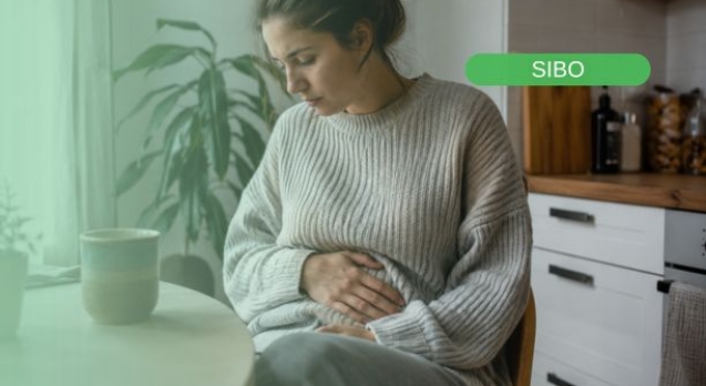 Mujer padeciendo uno de los síntomas más fracuentes del sibo: hinchazón abdominal y malestar digestivo